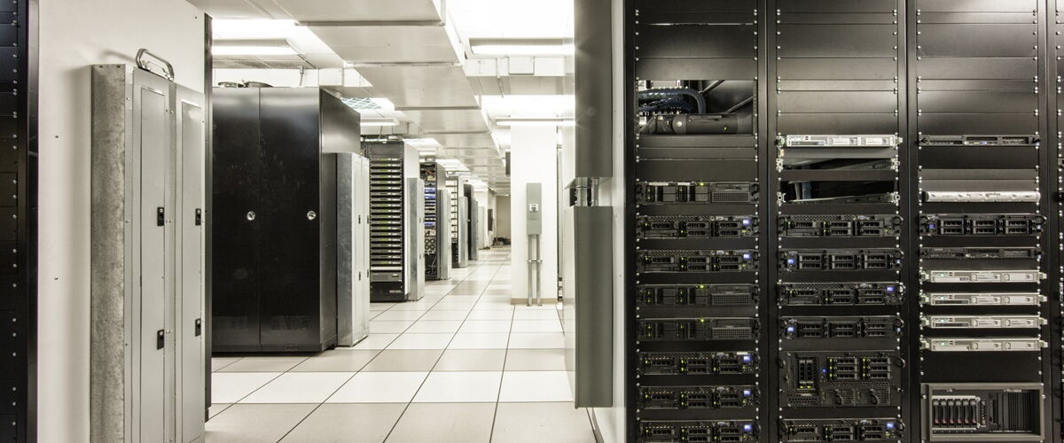 An aisle between rows of storage racks and cabinets in a data centre.