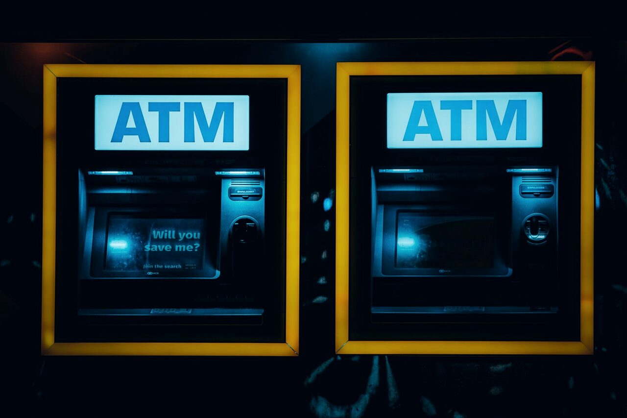 Two illuminated ATMs set into a wall at night.