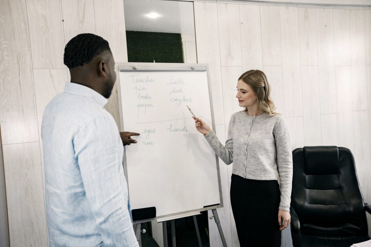 Two people planning together at a whiteboard during a training session.