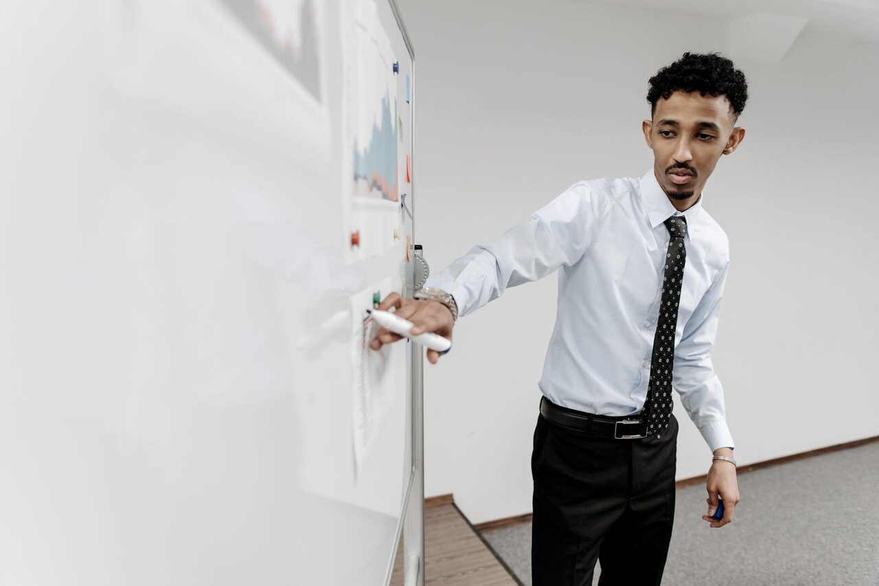 An instructor presenting at a whiteboard to a class.