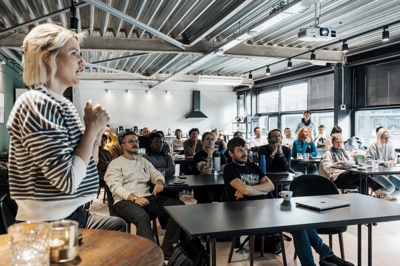A presenter addressing a room of colleagues at a workplace workshop.