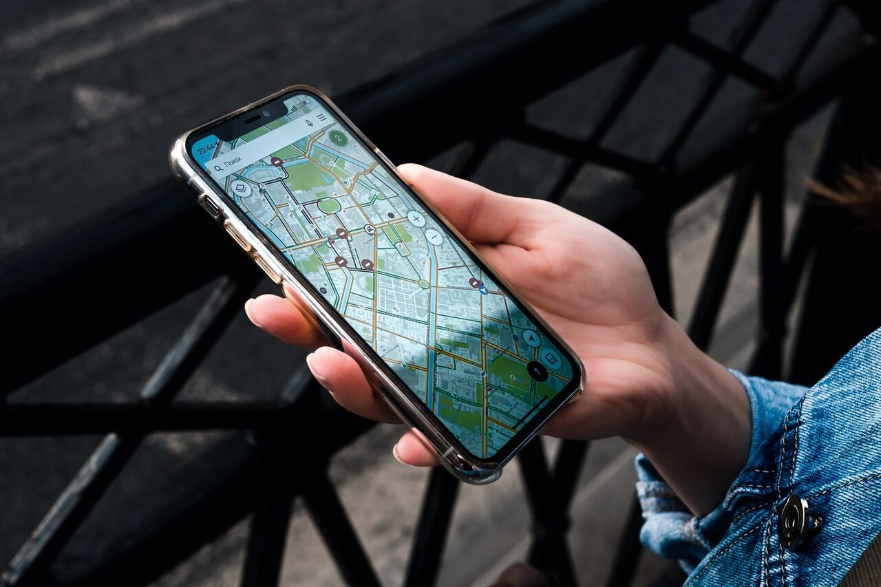 A hand holding a smartphone showing a street map with a location marker.