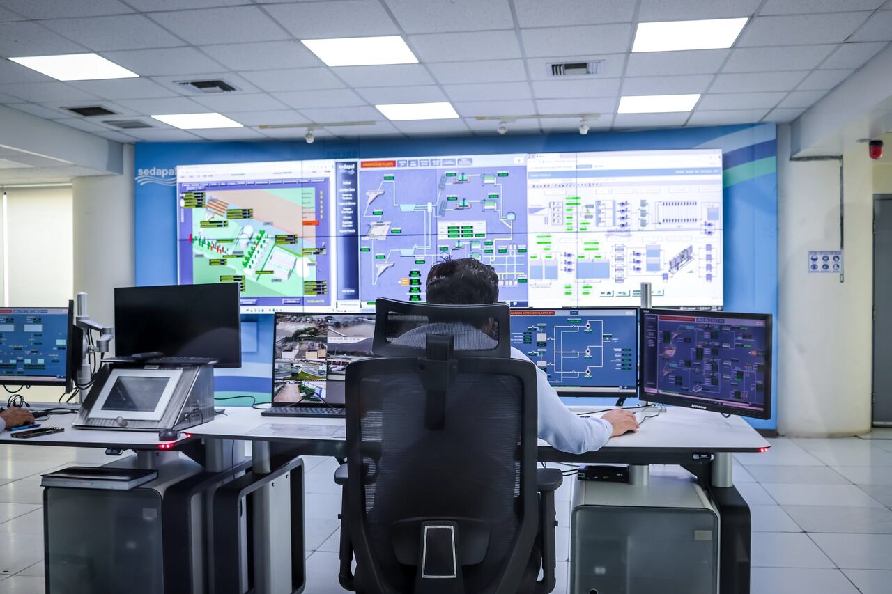 An operator overseeing a control room dominated by a large screen wall.
