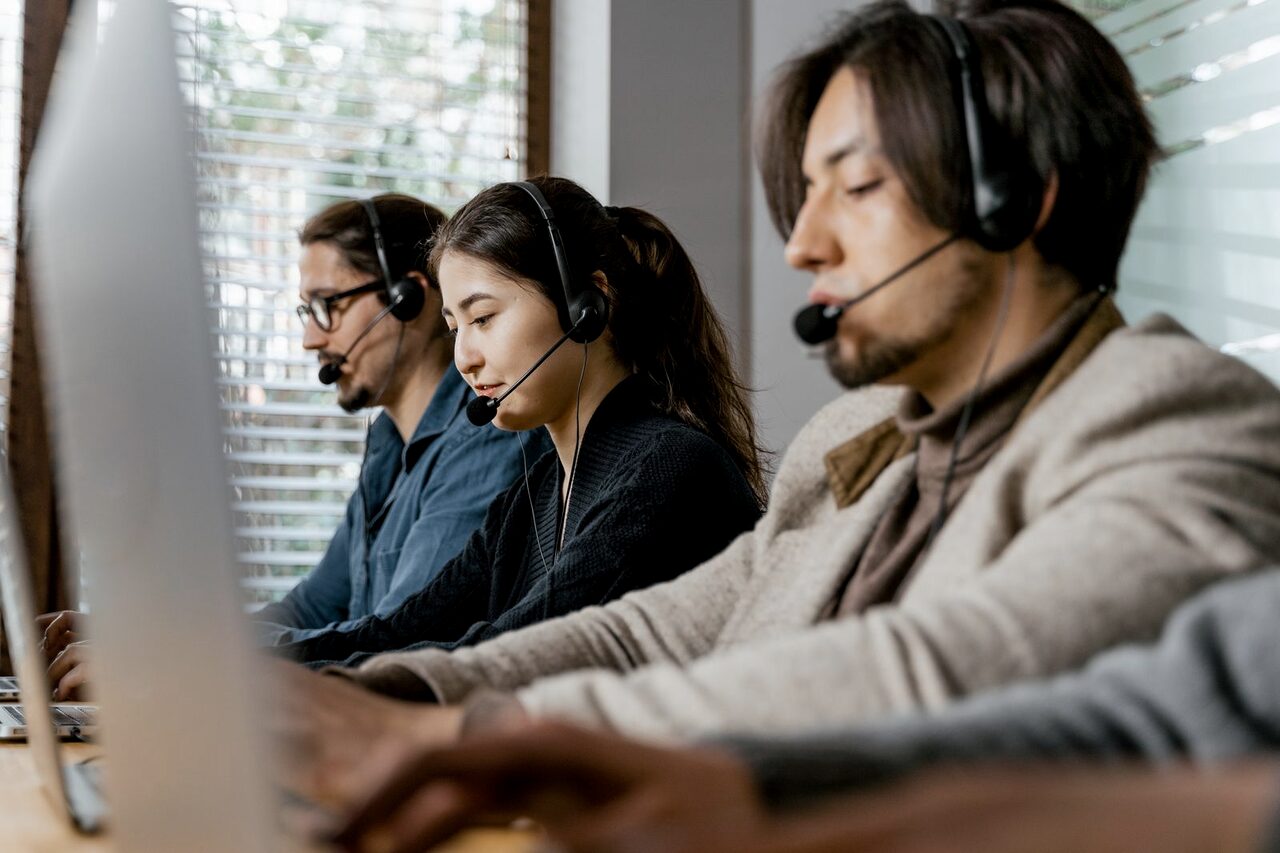 A row of headset-wearing agents working side by side in a call centre.