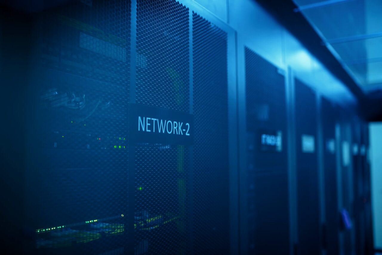 A dark server room with a network label glowing faintly across the racks.
